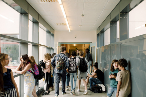Groups of middle school students standing near lockers and walking through school corridor